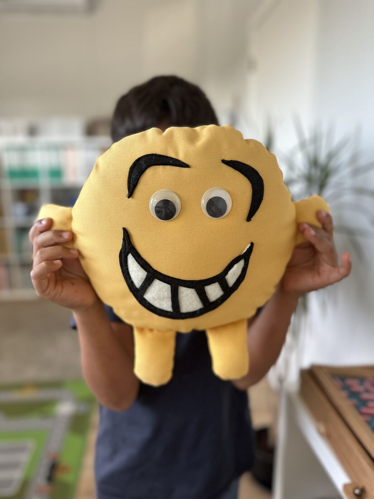 Criança a segurar uma almofada amarela com um grande sorriso