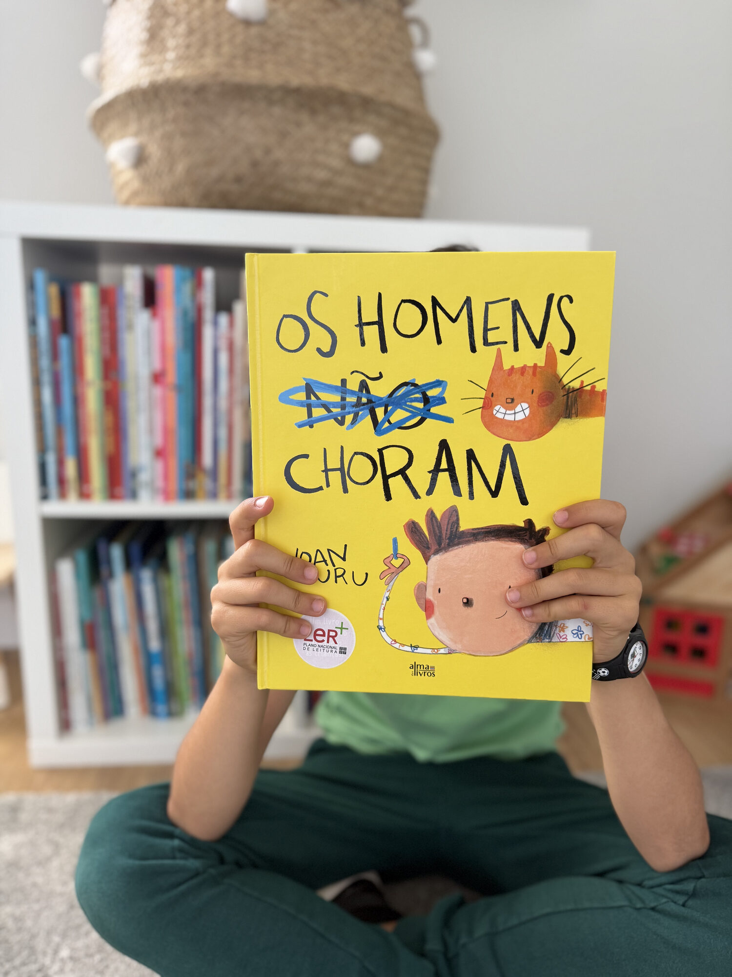 Rapaz sentado com o livro «Os homens não choram»