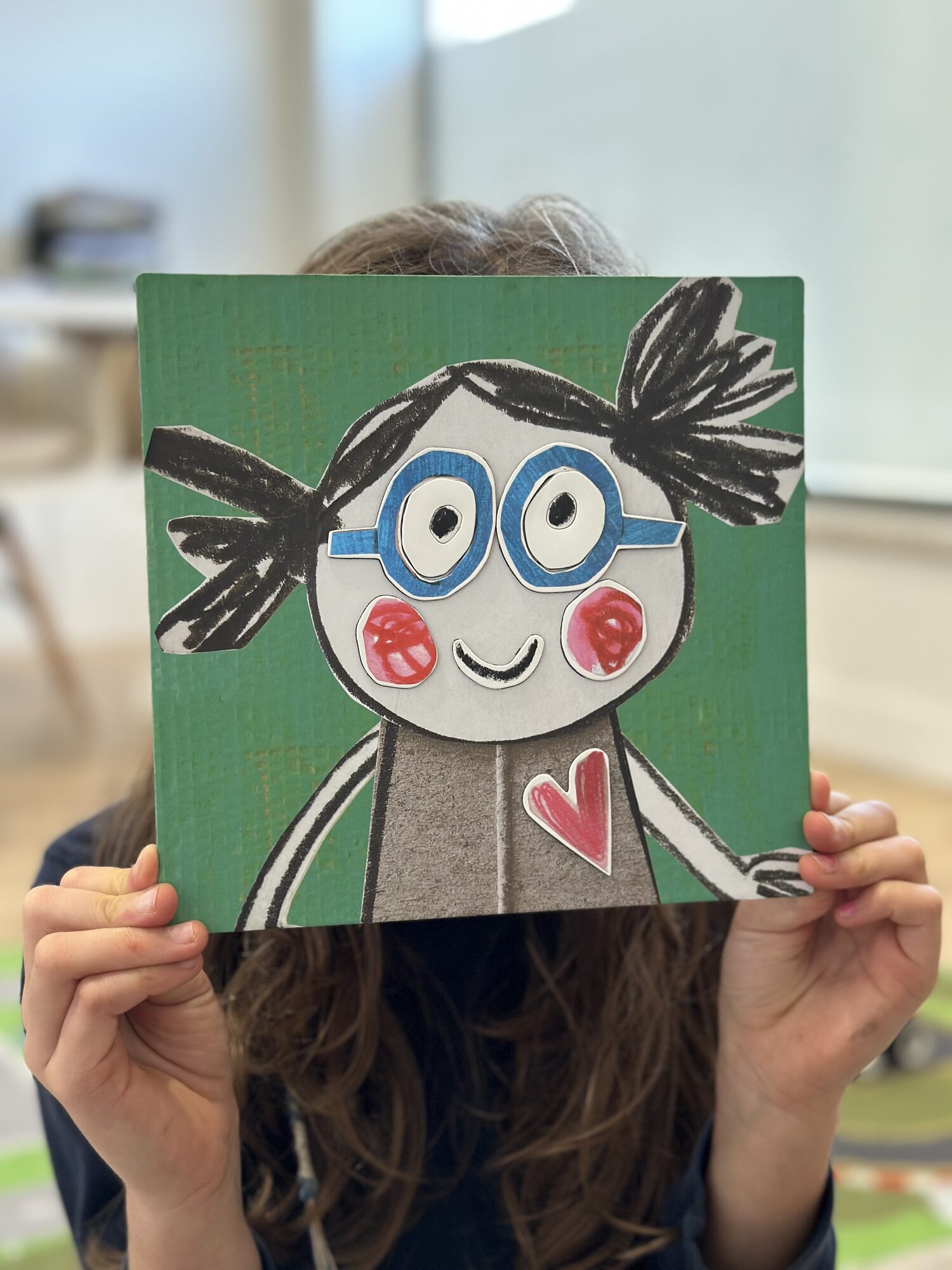 Criança e boneca com óculos junto a um quadro